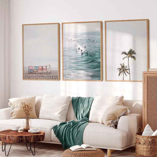 Coastal beach wall art set of 3 prints featuring beach chairs, surfers riding waves, and palm trees.