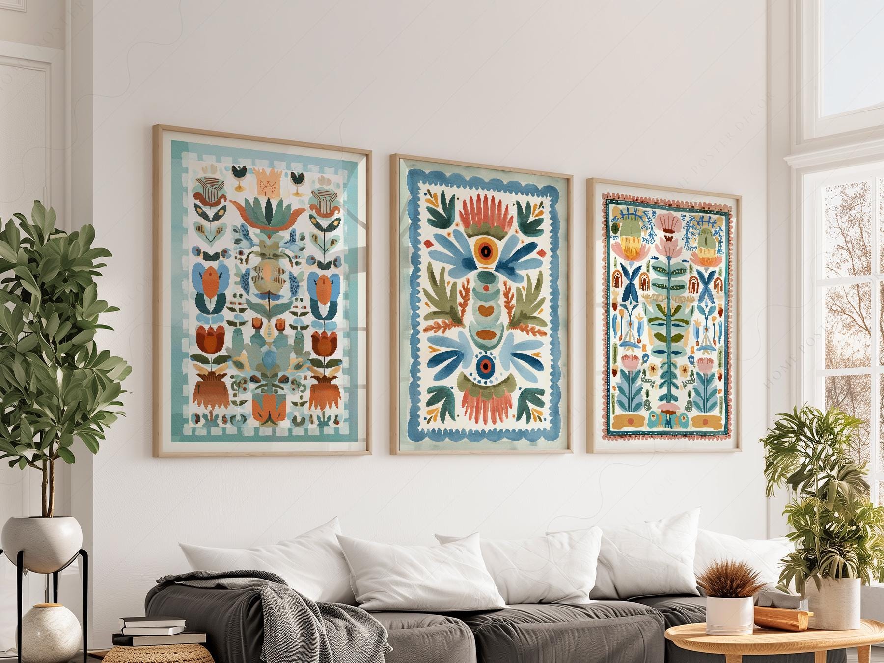 Set of three boho folk art floral prints with tapestry-style botanical designs displayed as wall art above a sofa.