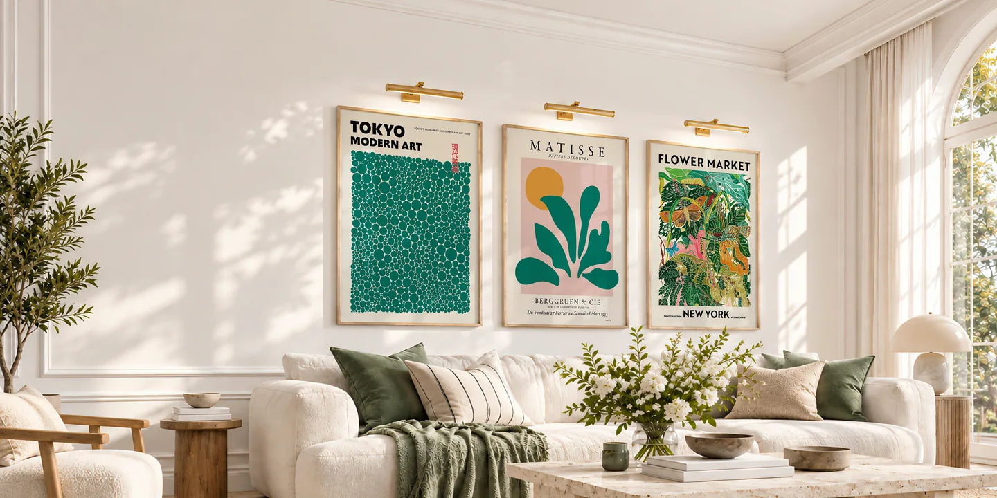 Three green and colourful framed art prints above a cream sofa in a sunlit living room.